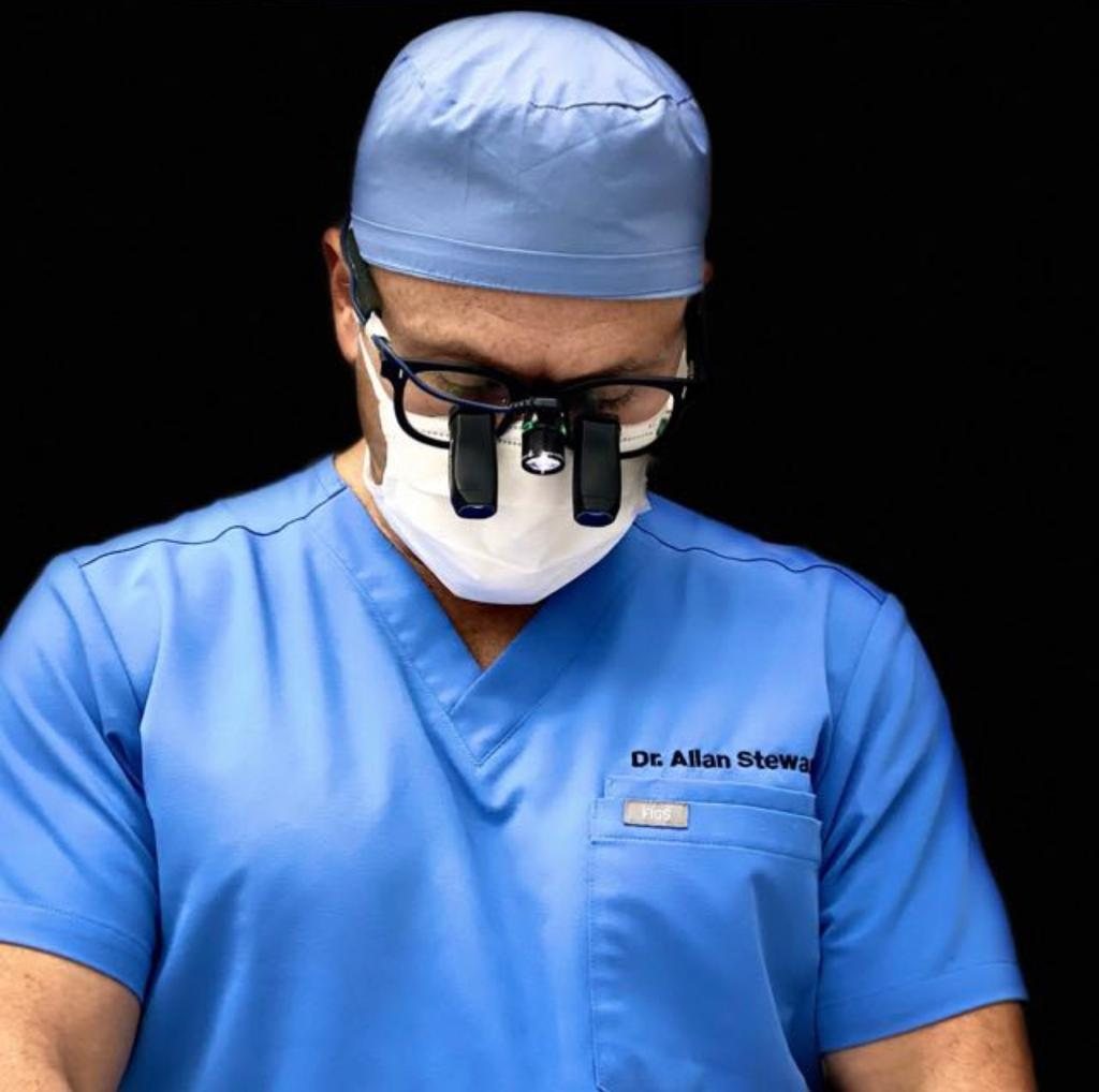 Dr. Allan Stewart in surgical scrubs and loupes